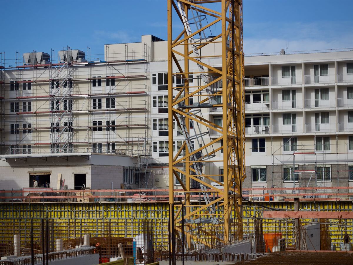 Edificio residencial en construcción con andamios y grúa amarilla